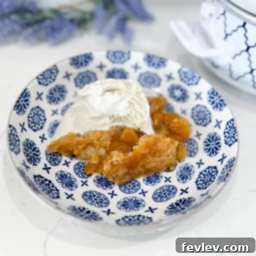 Effortless Peach Perfection 2 A golden slow cooker peach cobbler served warm in a bowl with a generous scoop of melting vanilla ice cream on top, ready to be enjoyed.