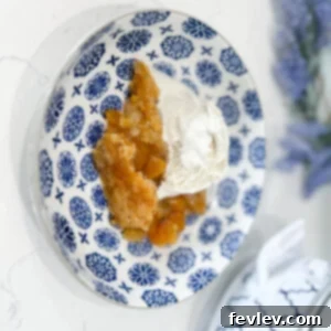 Effortless Peach Perfection 3 Close-up of a warm slow cooker peach cobbler with a golden topping, ready to be served with vanilla ice cream.