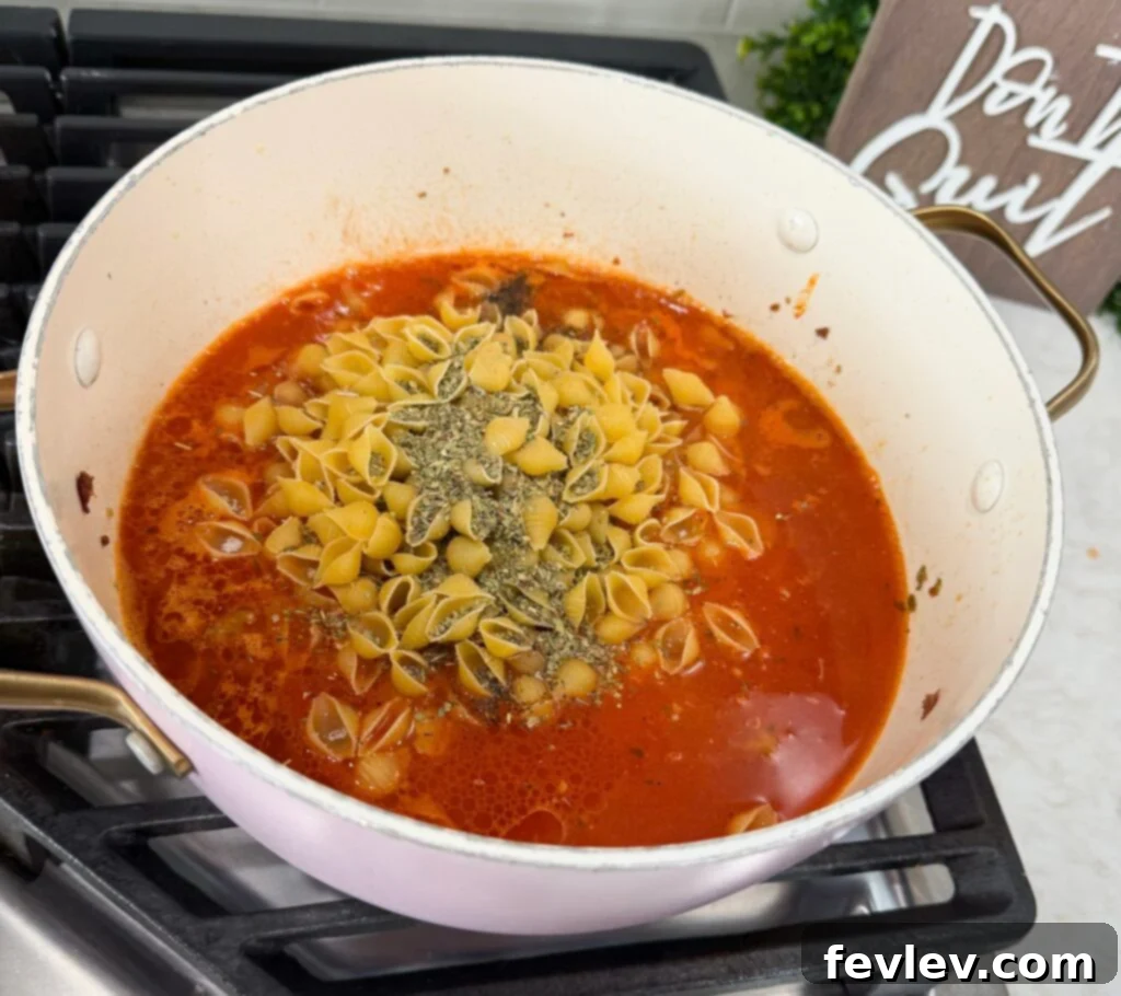 Speedy Skillet Sausage Pasta 3 Ground Italian sausage browning in a large pot on the stove, releasing aromatic flavors.