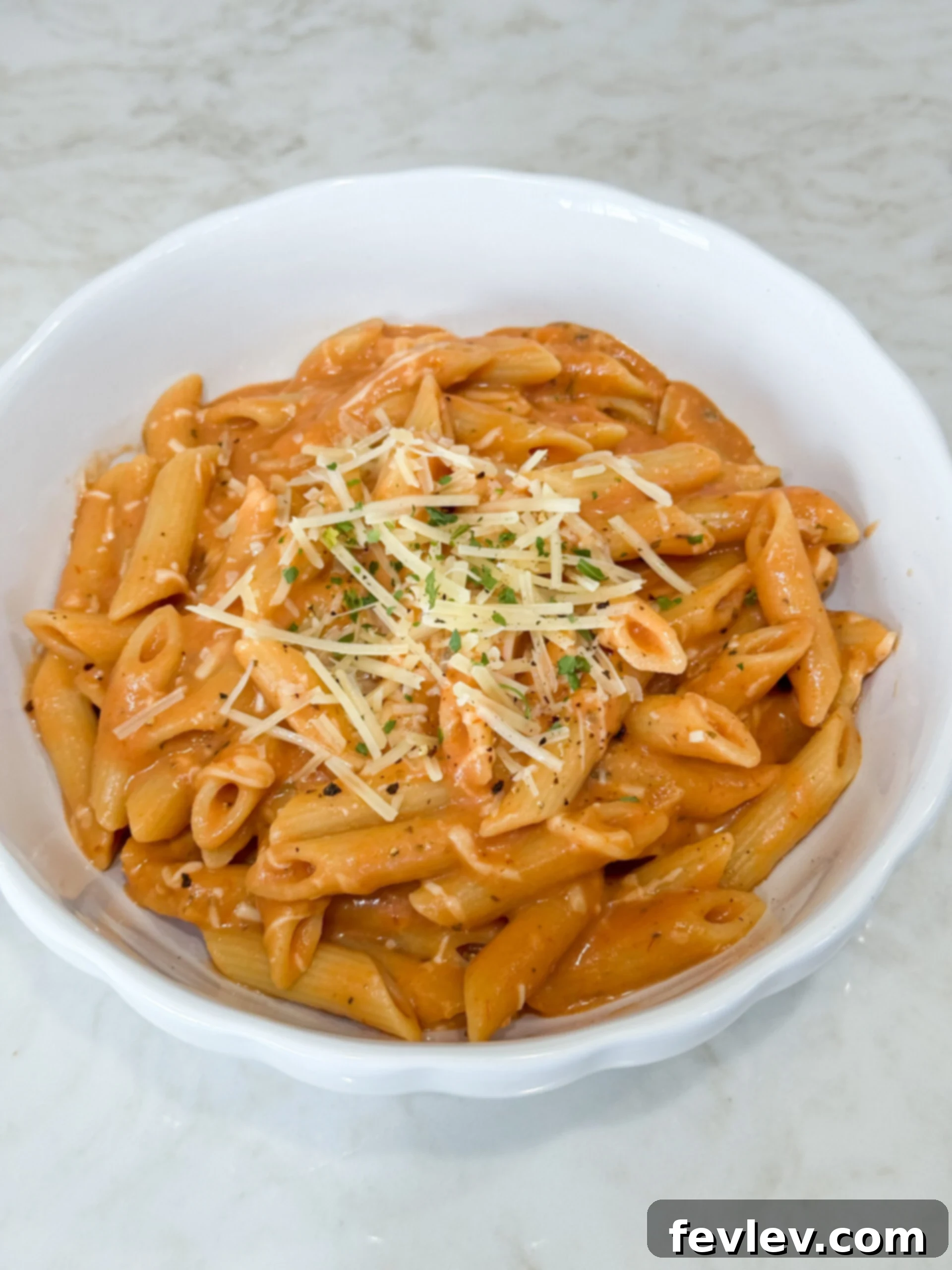 Effortless One Pot Creamy Pasta 2 Close-up of creamy penne pasta in a pot with melted cheese on top, garnished with fresh parsley.