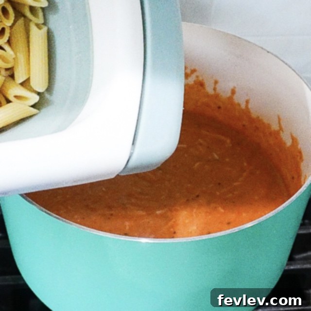 Effortless One Pot Creamy Pasta 5 Shredded mozzarella and grated Parmesan cheese being stirred into the simmering creamy pasta sauce, creating a smooth and rich texture.