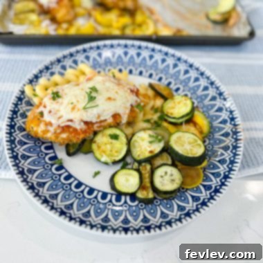 Sheet Pan Marinara Mozzarella Chicken Zucchini Bake 2 Close-up of golden brown sheet pan chicken topped with vibrant marinara and bubbly melted mozzarella, served alongside beautifully roasted green zucchini and yellow squash, creating an appetizing Italian-inspired meal.