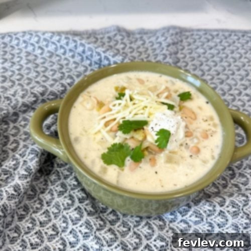 Velvety Slow Cooker White Chicken Chili 2 A steaming bowl of Creamy White Chicken Chili, garnished with fresh cilantro and a lime wedge, ready to be enjoyed.