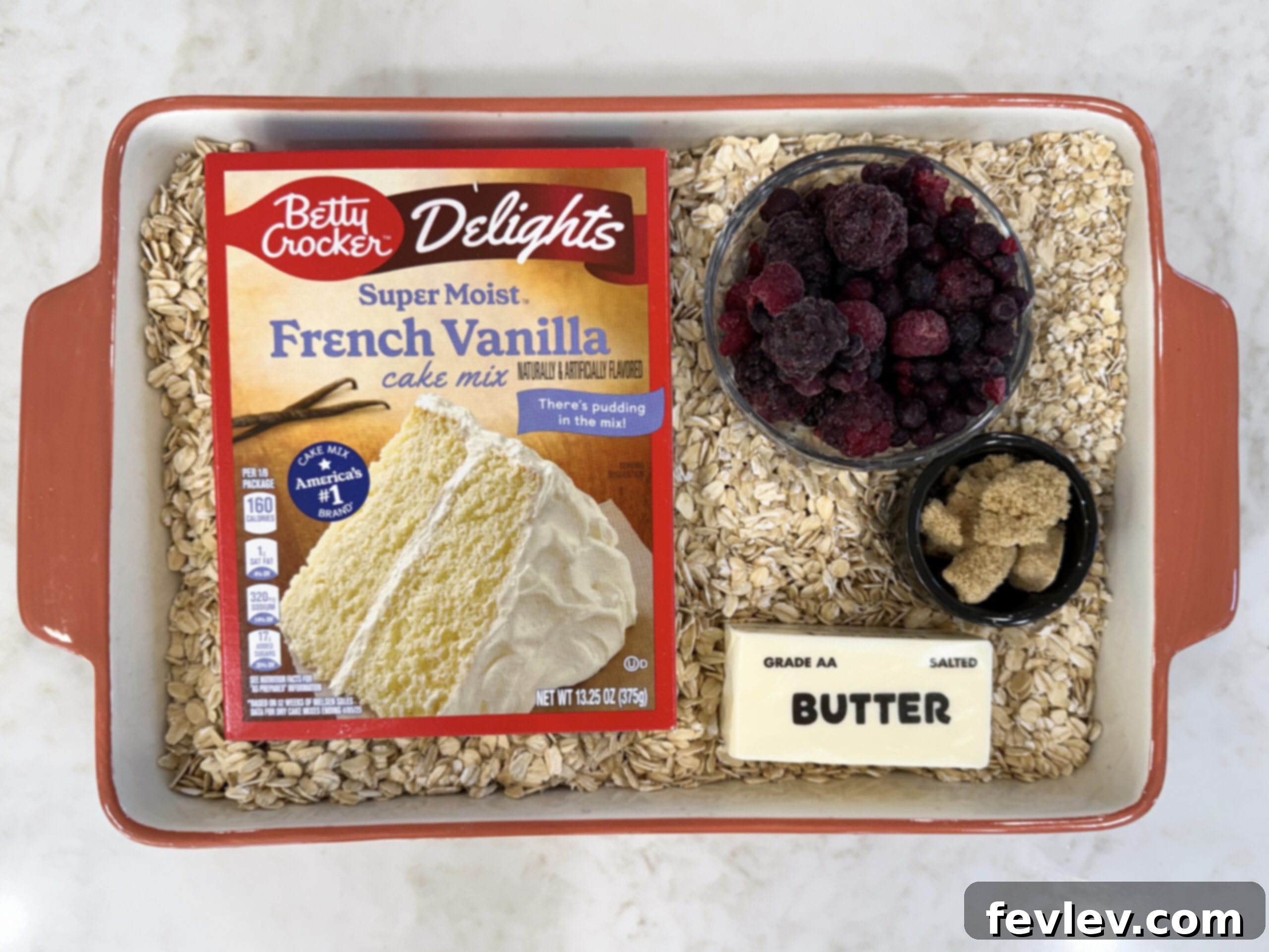 Perfect Homemade Berry Cobbler 5 Ingredients for easy berry cobbler, including frozen berries, cake mix, oats, brown sugar, and butter, arranged in a casserole dish before baking.