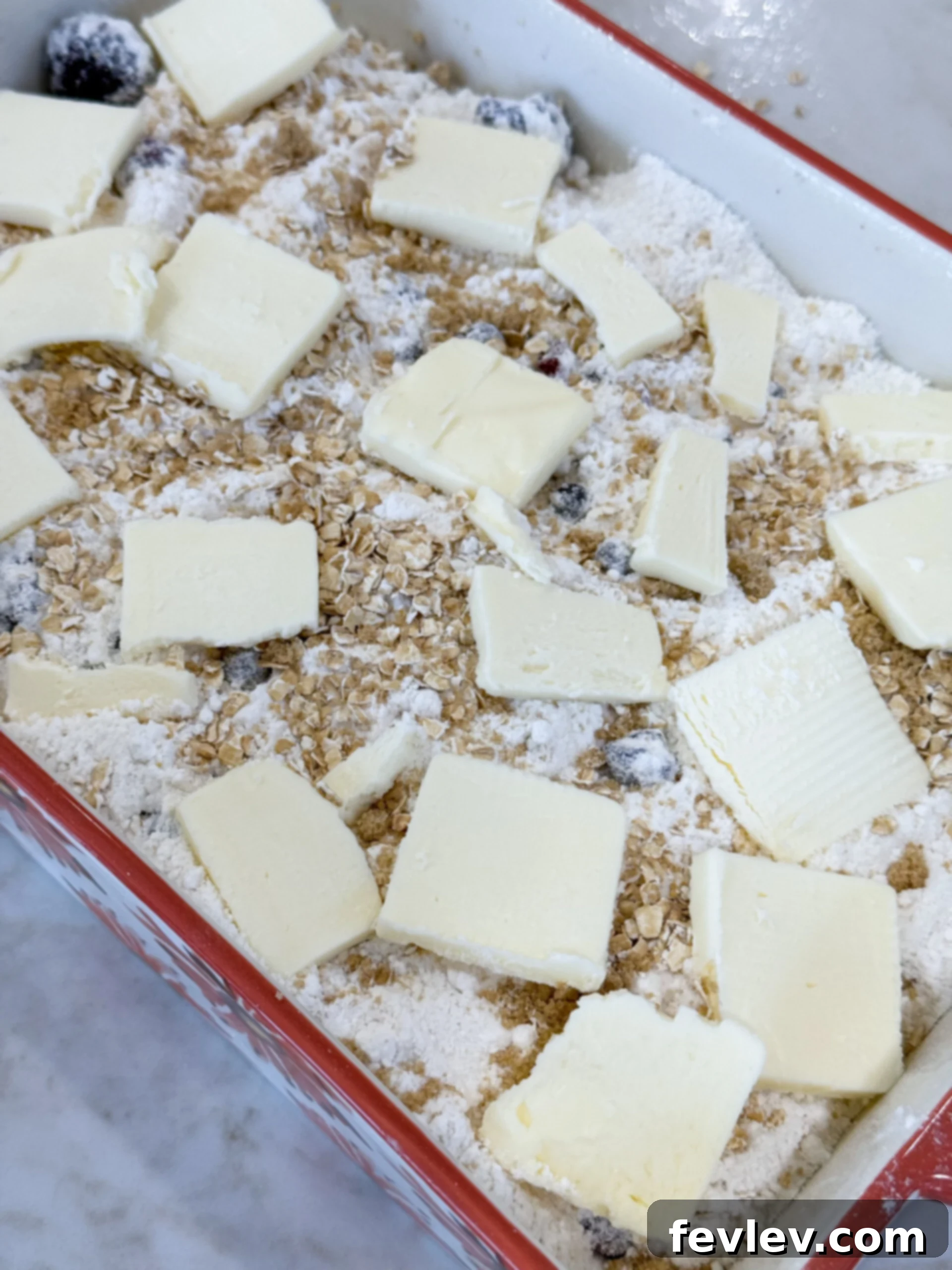 Perfect Homemade Berry Cobbler 7 Adding thinly sliced cold butter evenly over the dry cake mix layer of the berry cobbler before baking to achieve a golden, buttery crust.