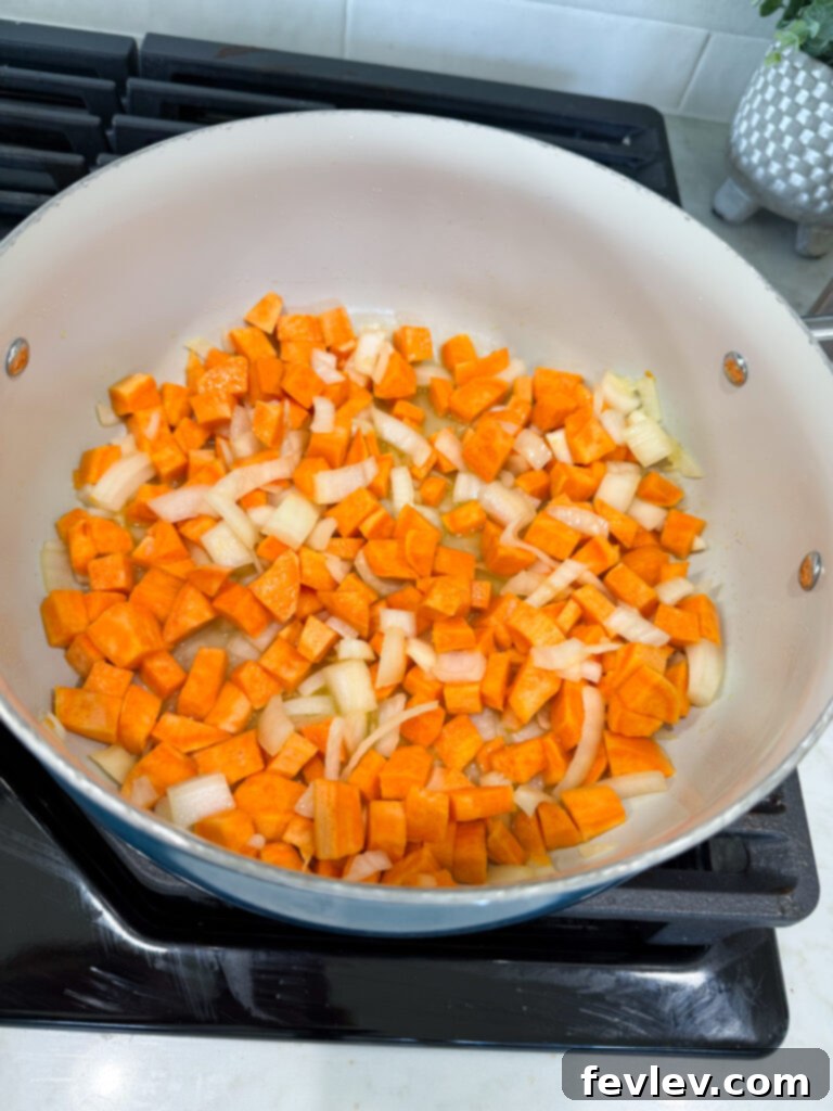 Sweet potatoes and onions simmering in broth, covered by a lid
