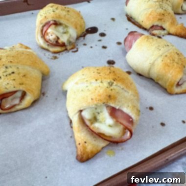 Golden-baked Chicken Cordon Bleu Pockets on a baking sheet, showing a flaky crust and melted Swiss cheese peeking out, ready to serve as an easy dinner or appetizer.