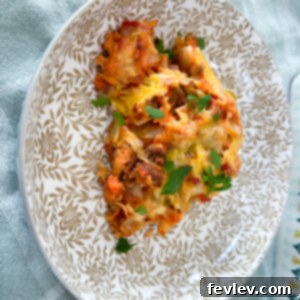A hearty Shipwreck Casserole, layered with ground beef, vegetables, potatoes, and melted cheddar cheese, freshly baked in a dish.