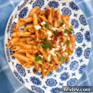 Delicious Cheesy Bacon Pasta in a bowl, garnished with fresh herbs