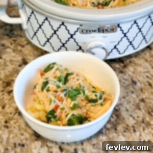 Creamy Slow Cooker Alfredo Tuscan Chicken with spinach and sun-dried tomatoes, served with pasta