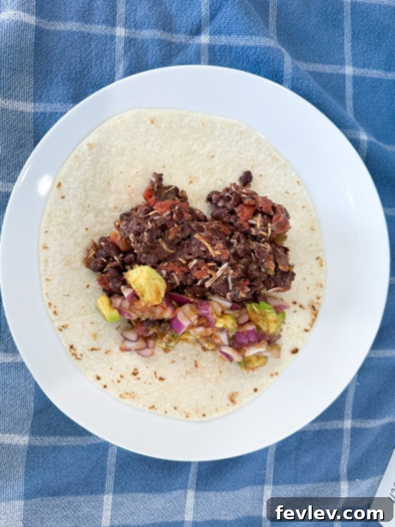 Black Bean Fiesta Burritos 5 Two freshly rolled black bean burritos with avocado salsa on a plate