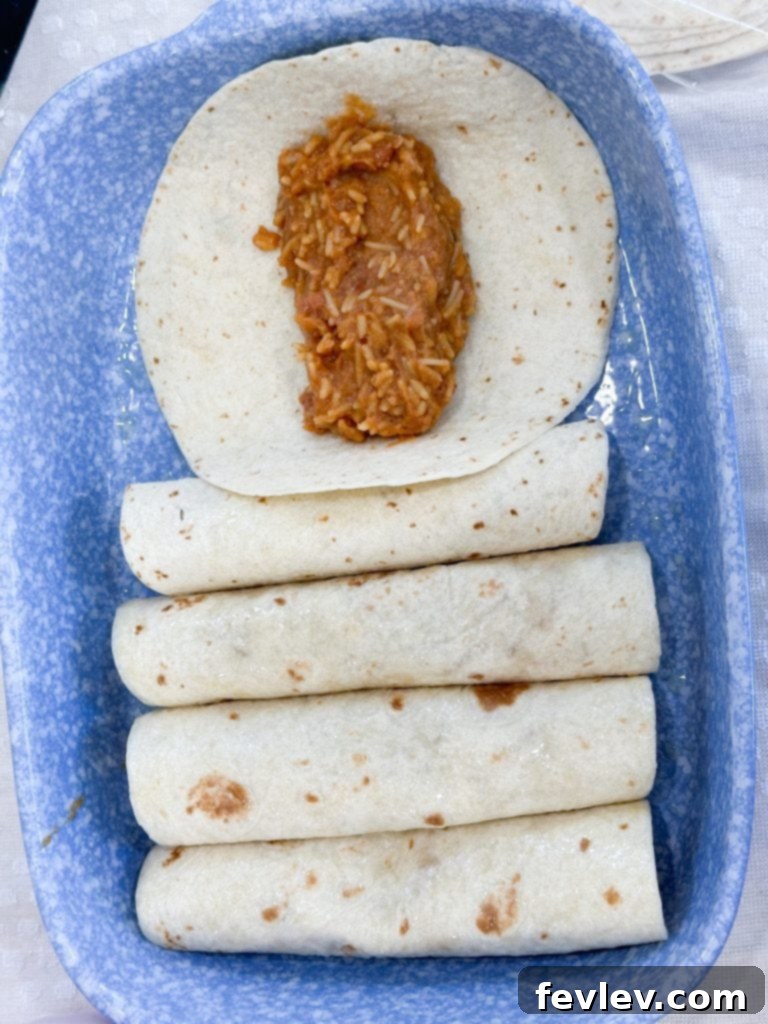 Assembling bean and rice enchiladas in a baking dish