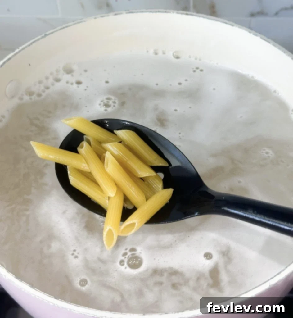 Bacon Tomato Pasta on a Budget 3 Penne pasta cooking in a large pot of boiling water.