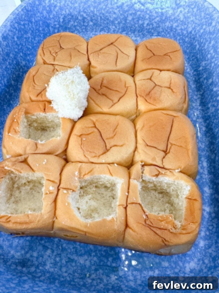 Hawaiian rolls with square cutouts in the center, prepared for the cream cheese filling.