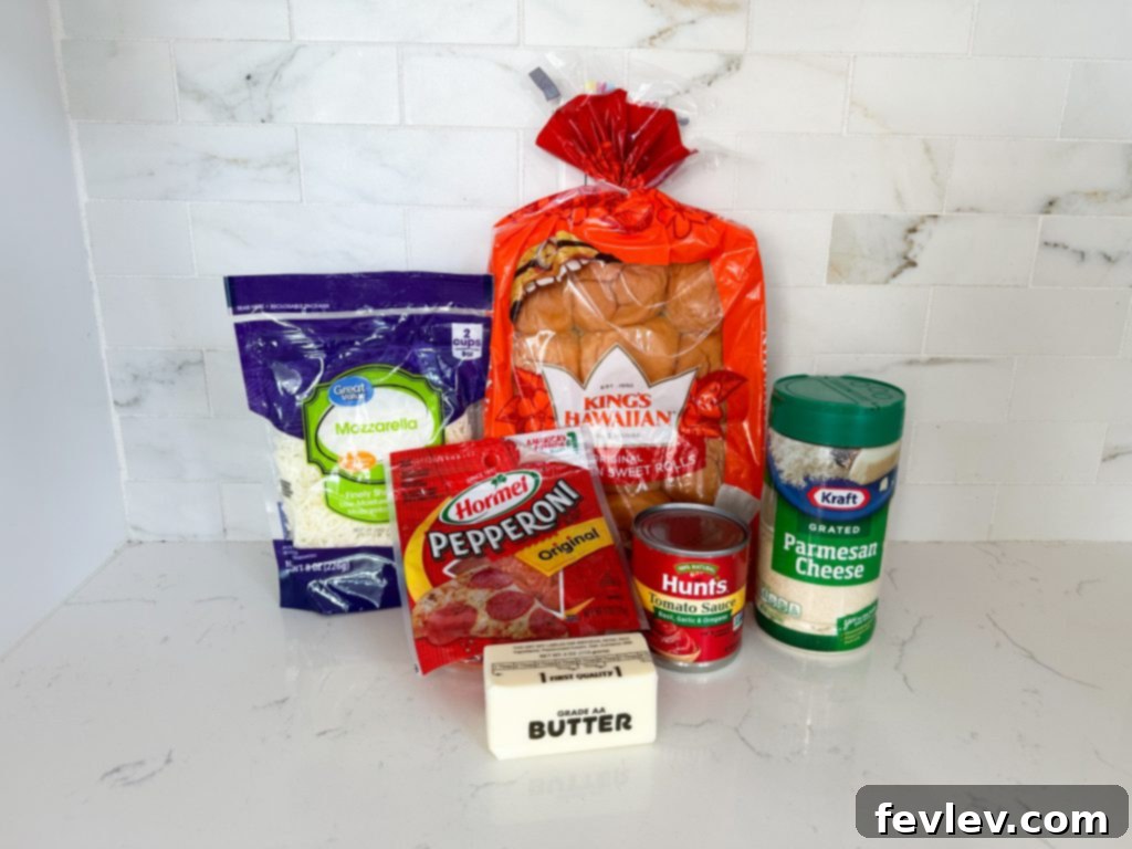 Mini Pizza Melts 2 Ingredients laid out for making pizza sliders, including Hawaiian rolls, shredded mozzarella, pepperoni, pizza sauce, butter, and Italian seasoning.