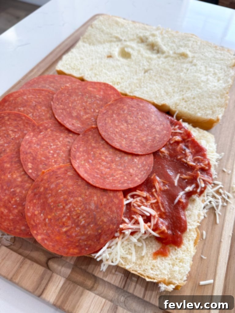 Mini Pizza Melts 3 The bottom half of a package of Hawaiian rolls, neatly sliced horizontally, placed in a baking dish, ready for the first layer of toppings.