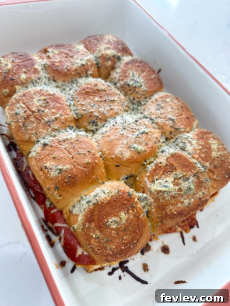 Mini Pizza Melts 5 A pastry brush applying the melted butter, Parmesan, and Italian seasoning mixture evenly over the top of the unbaked pizza sliders.