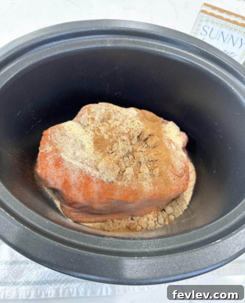 Seasoned pork shoulder roast placed into a slow cooker