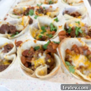 A perfectly portioned mini beef taco cup, showcasing the golden tortilla, seasoned beef, and melted cheese, garnished with fresh cilantro.