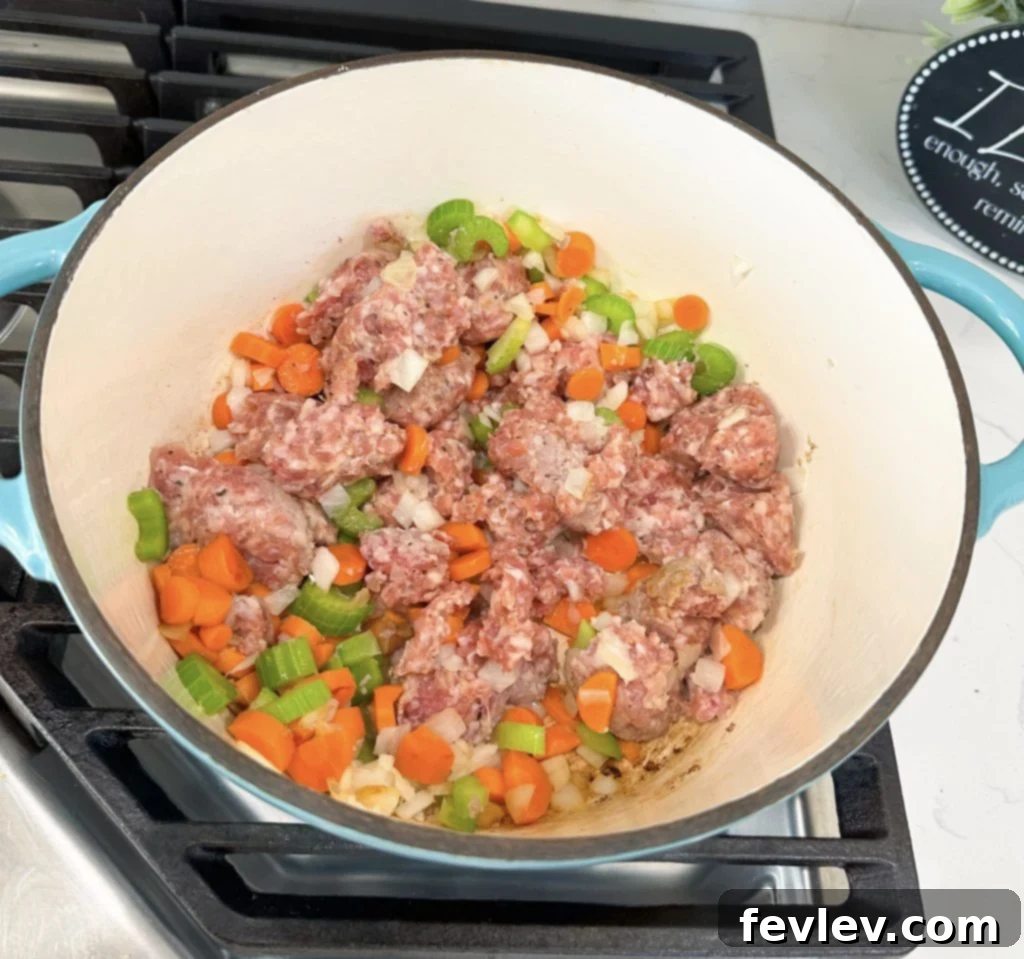 Cooking Italian sausage, diced onions, carrots, and celery in a large Dutch oven for a one-pot soup