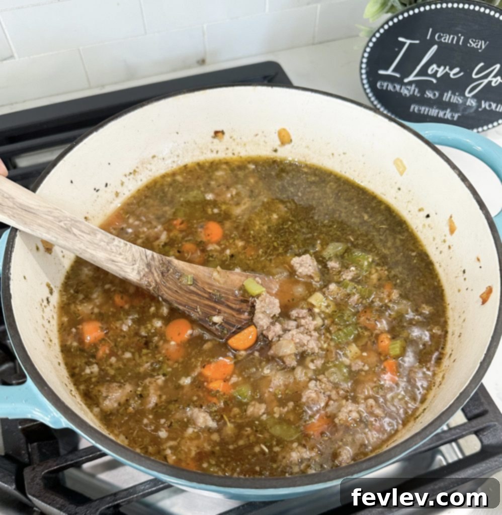 Italian sausage and vegetables simmering with broth and seasonings in a pot