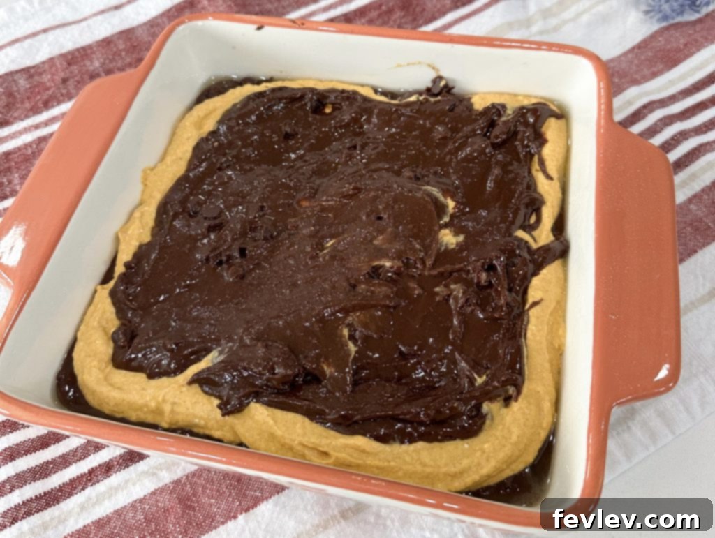 Remaining brownie batter spread over the pumpkin layer, creating a top chocolate layer.