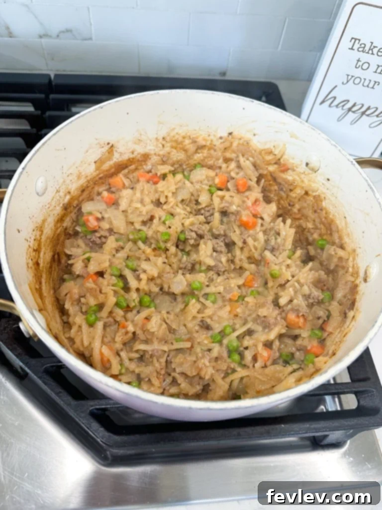 Ground turkey and diced onions cooking in a large skillet for cheeseburger hash brown casserole