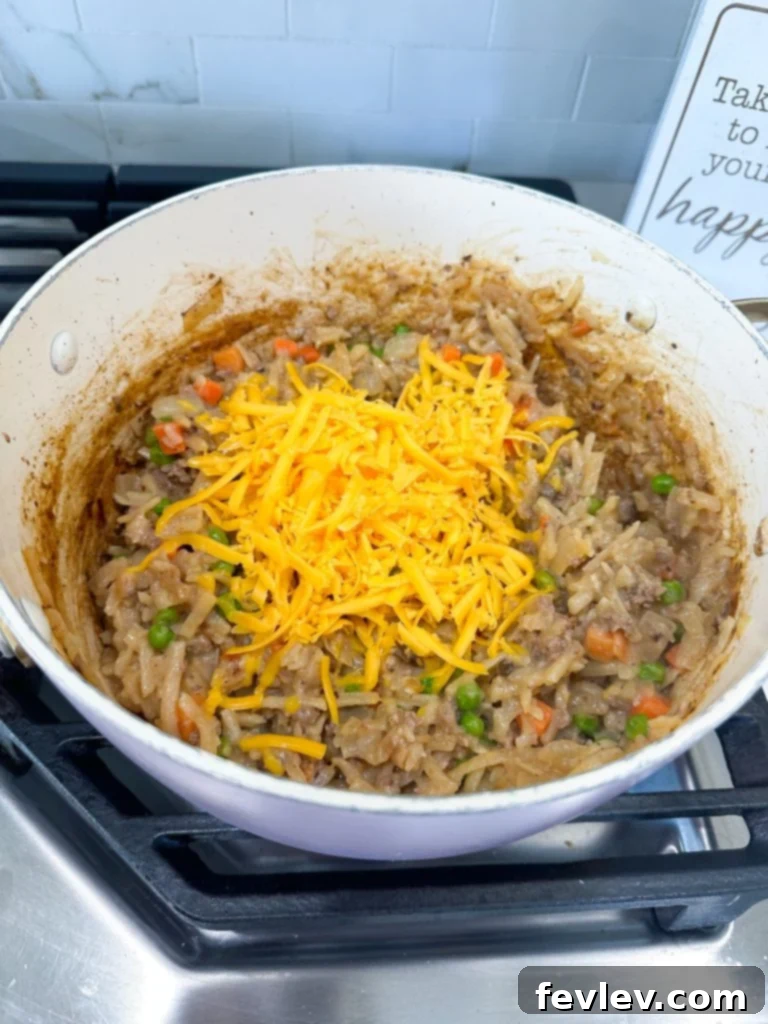Mixing all ingredients in a skillet for Cheeseburger Hash Brown Casserole
