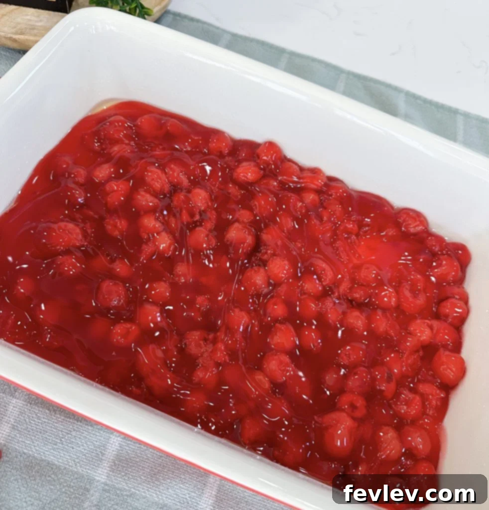 Spreading cherry pie filling evenly in a 9x13 inch baking dish, the first layer of the Black Forest Dump Cake