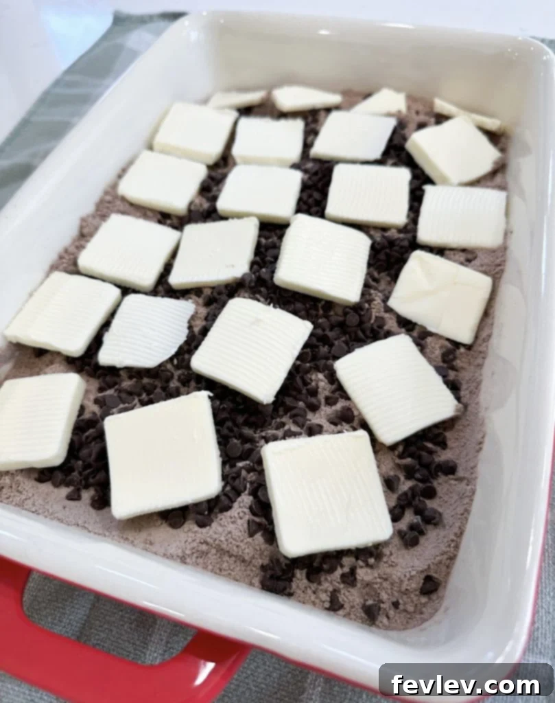 Placing thinly sliced cold butter strategically over the dump cake to ensure even moistness and a golden crust