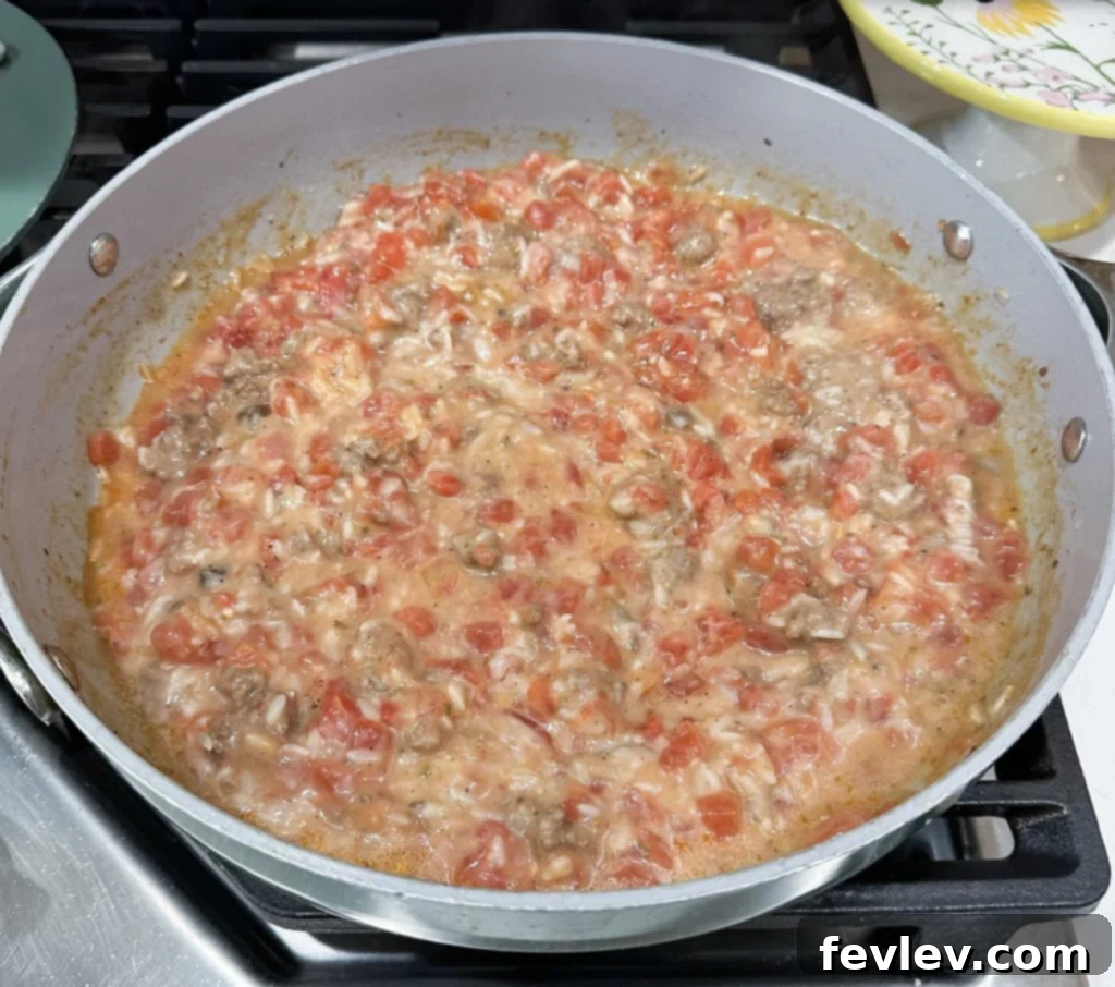 Cooking hamburger rice casserole in a large skillet, showing all ingredients mixed and simmering.
