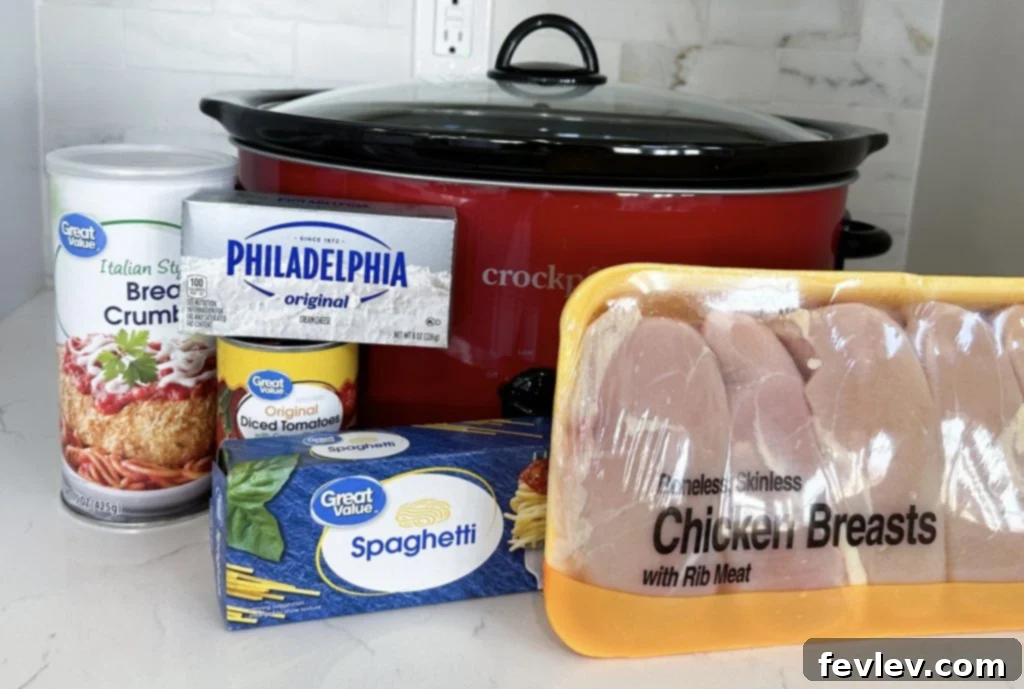 Creamy Slow Cooker Chicken Spaghetti 2 All the core ingredients laid out for Slow Cooker Chicken Spaghetti, including canned soups, diced tomatoes, various cheeses, Italian seasoning, chicken breasts, and uncooked spaghetti.