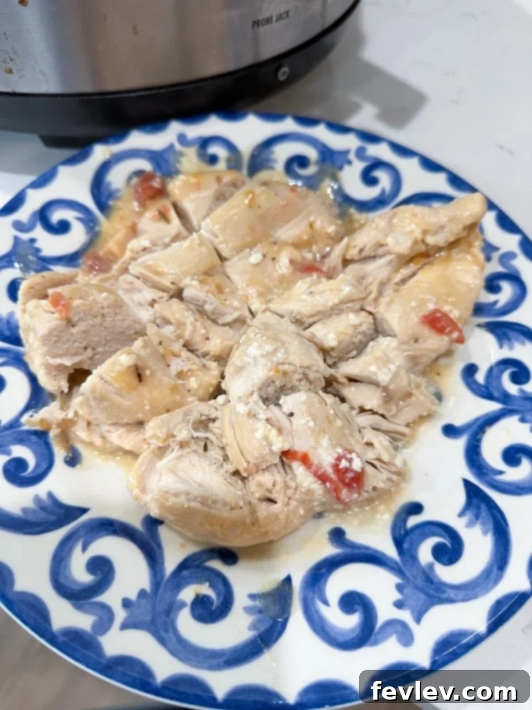 Creamy Slow Cooker Chicken Spaghetti 4 Shredded chicken being returned to the creamy sauce in the slow cooker for the chicken spaghetti recipe.
