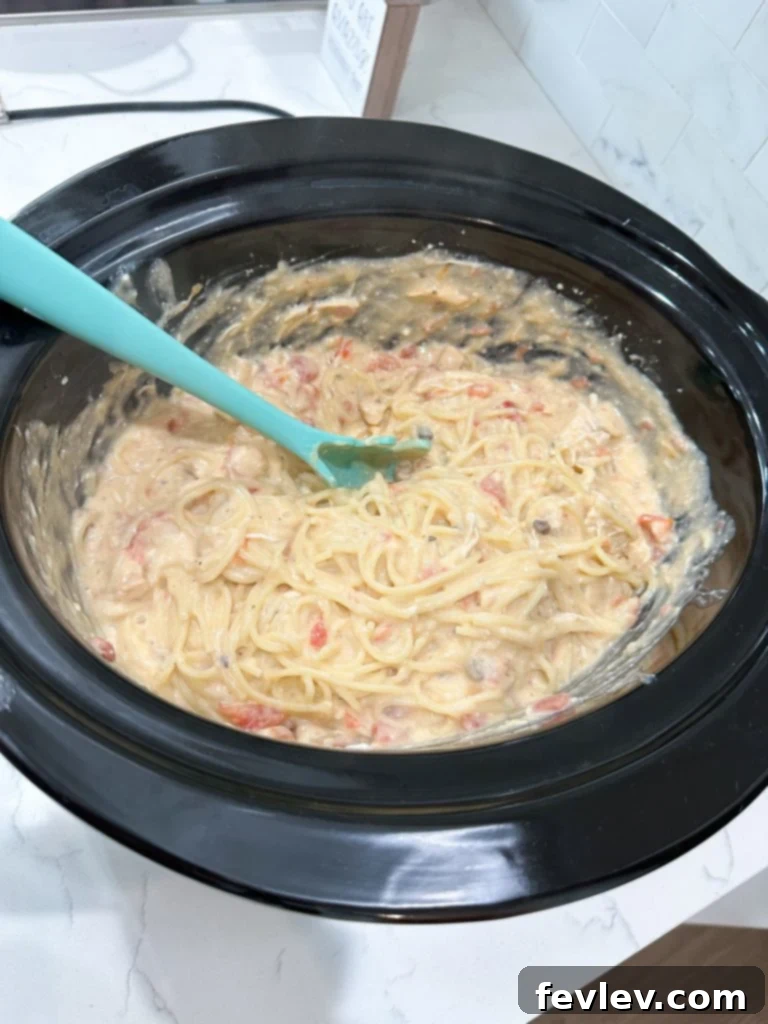 Creamy Slow Cooker Chicken Spaghetti 7 Finished Slow Cooker Chicken Spaghetti in the slow cooker, showing the melted cheese and creamy sauce mixed with pasta and chicken.