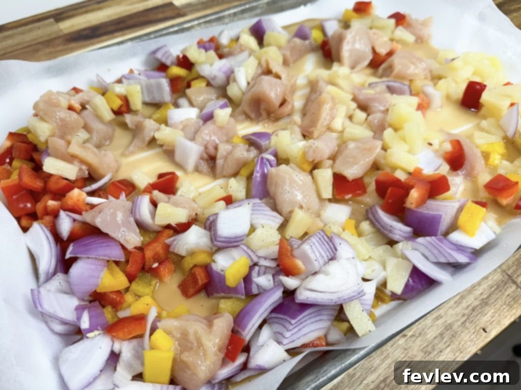 Tropical Sheet Pan Chicken Dinner 4 Sheet Pan Hawaiian Chicken with glaze poured over, ready for the oven.