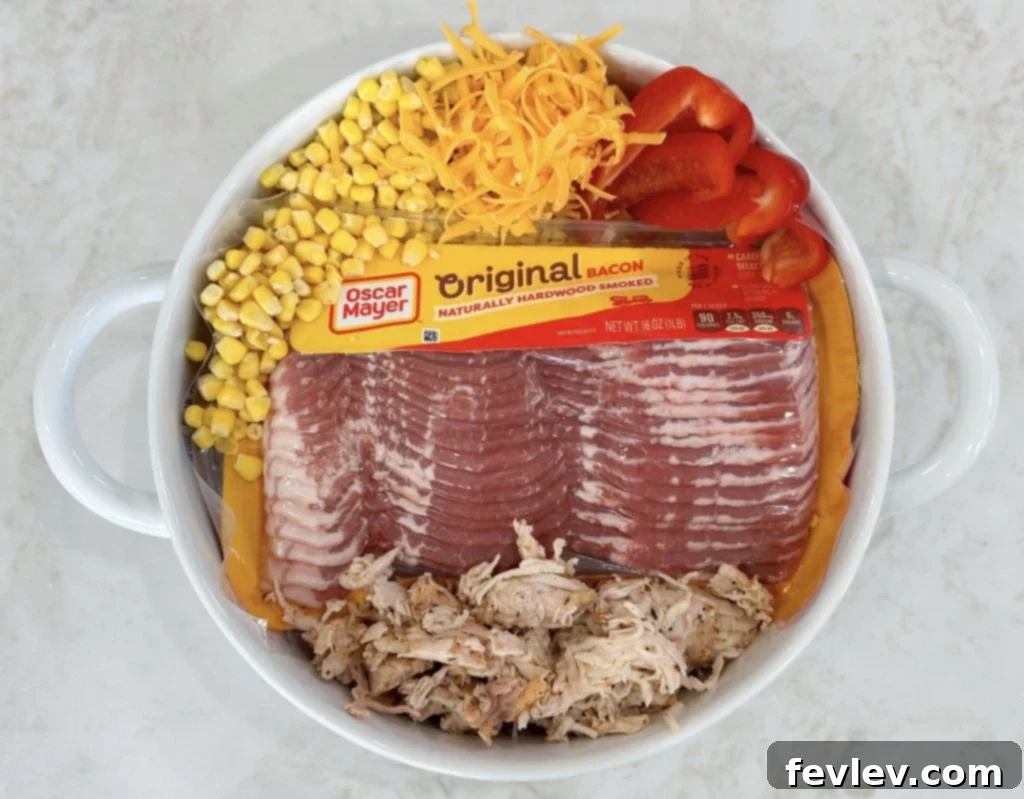 Assortment of fresh and prepped ingredients for chicken and vegetable casserole, including diced bell peppers, onions, shredded chicken, and cheeses.