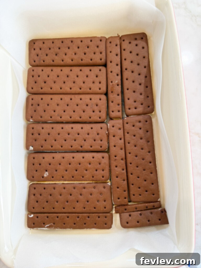 The first layer of unwrapped ice cream sandwiches being placed in a 9x13 baking dish for an easy no-bake cake.