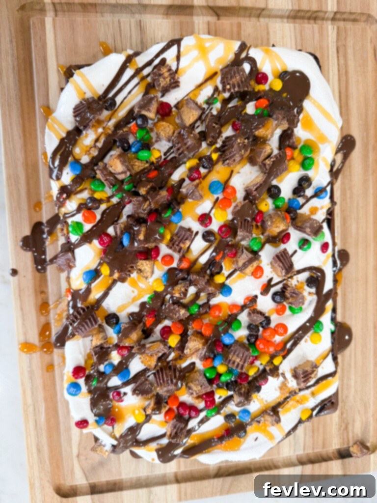 A beautifully topped ice cream sandwich cake resembling a monster cookie, with colorful mini M&M's and caramel drizzle.