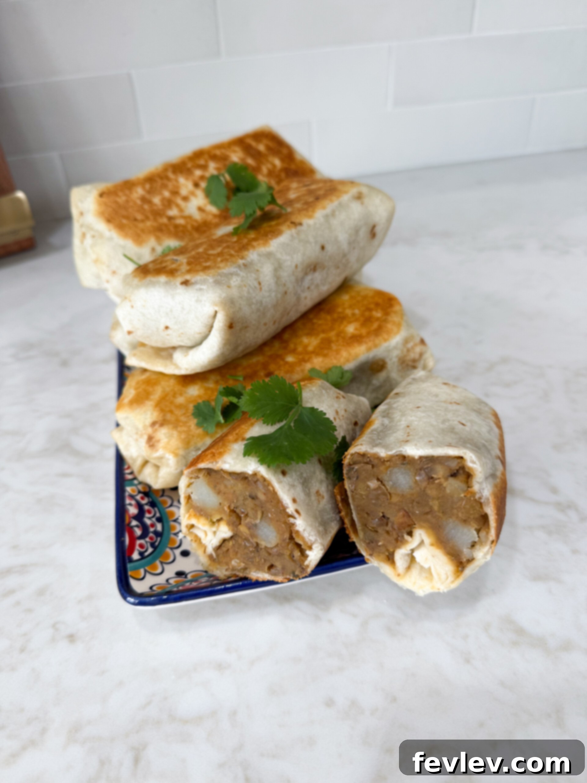 Stacked lentil and potato burritos on a plate, showcasing a delicious vegetarian meal.