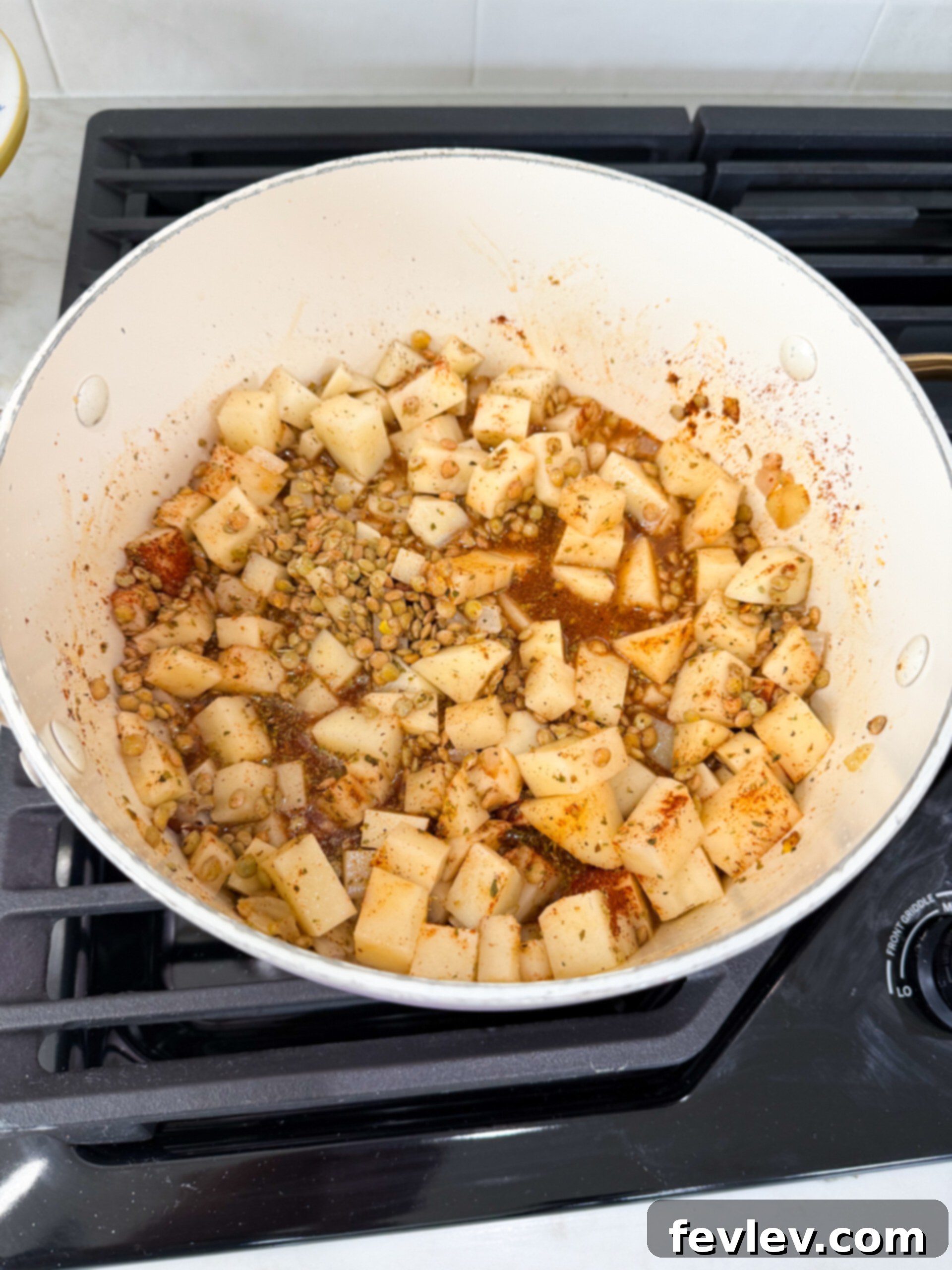 Cooked lentils and diced potatoes simmering in a pot, absorbing rich flavors.