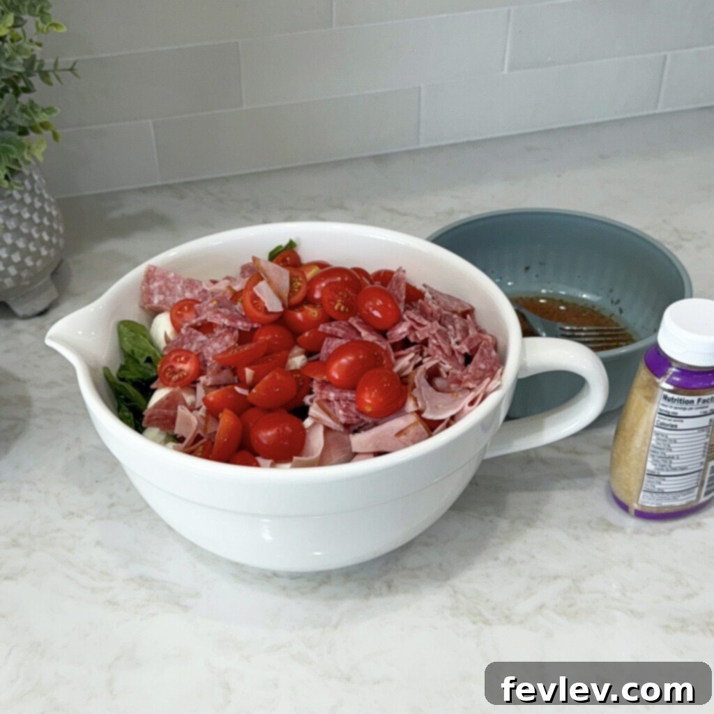 Adding all the antipasto ingredients to the bowl with the dressing