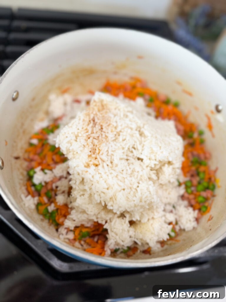 Quick and Delicious Ham Fried Rice 7 Adding cold rice to sautéed vegetables in a pan