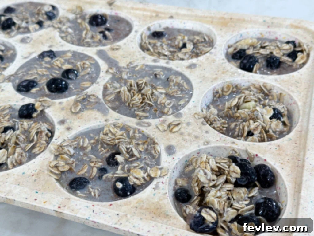 Effortless Breakfast Meal Prep 5 Unbaked blueberry oatmeal muffins perfectly portioned in a muffin tin, ready for the oven.