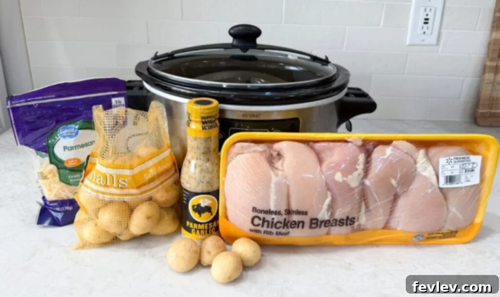 Parmesan Garlic Chicken and Potato Slow Cooker 4 Black and grey slow cooker on a counter with raw chicken, potatoes, with buffalo wing wings sauce and parmesan cheese