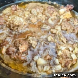 Cooked ground meat browned in a black slow cooker, ready to be drained.