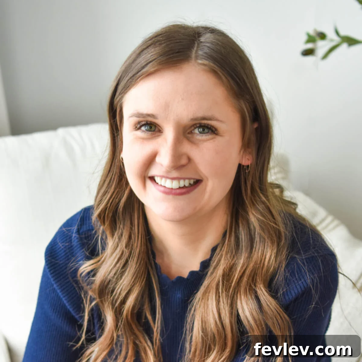 Julia Pacheco sitting in a white chair, a cookbook author and cooking enthusiast.