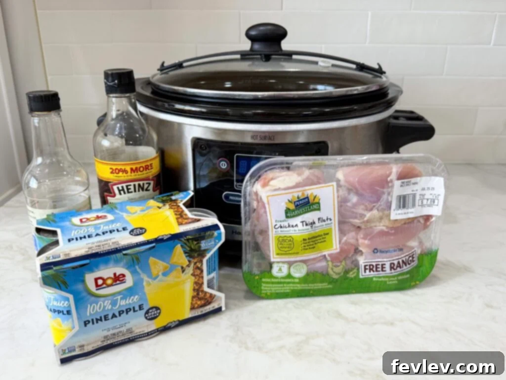 Large slow cooker filled with raw boneless, skinless chicken thighs submerged in bright yellow pineapple juice, ready to be cooked on a white kitchen counter.