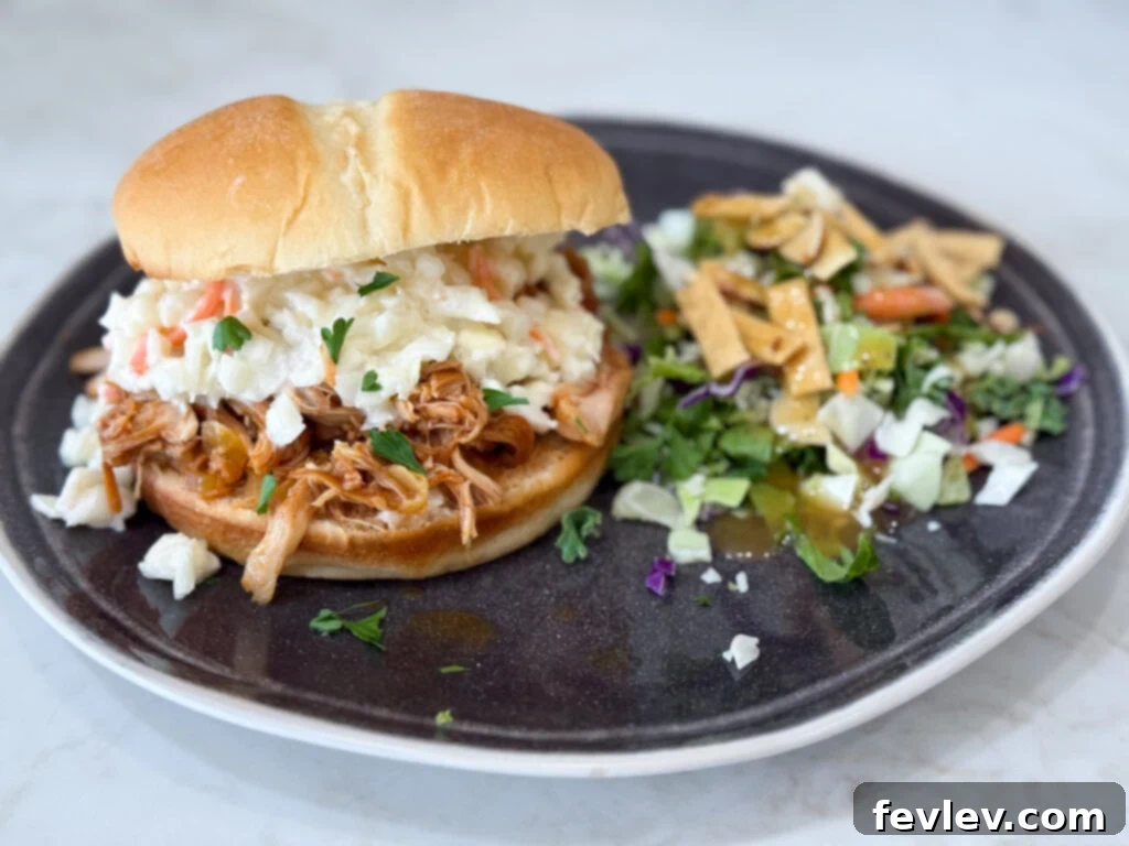 Slow cooker Hawaiian barbecue chicken sandwiches on a black plate with salad