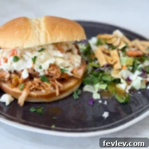 Slow cooker Hawaiian barbecue chicken sandwiches on a black plate with salad