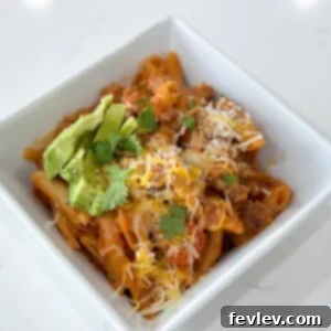 One-pot ground turkey pasta, a cheesy and spicy dish with a creamy tomato sauce, garnished with fresh cilantro, making for an easy and delicious meal.